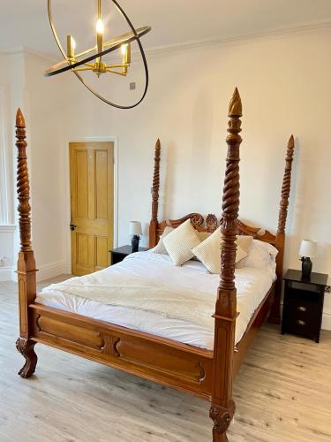 a bedroom with a wooden bed with a chandelier at Fayhomes West Midlands Luxury Late 1800 Property in Walsall