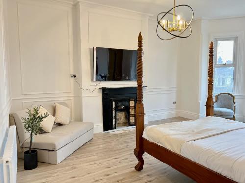 a bedroom with a bed and a couch and a fireplace at Fayhomes West Midlands Luxury Late 1800 Property in Walsall