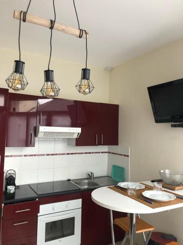 une cuisine avec des placards violets, une table et des lumières dans l'établissement SUPER APPARTEMENT PLAGE BERCK, à Berck-sur-Mer