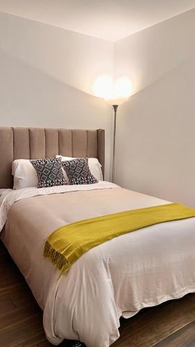 a bedroom with a bed with a yellow blanket on it at Departamento nuevo en el corazón de la Condesa in Mexico City