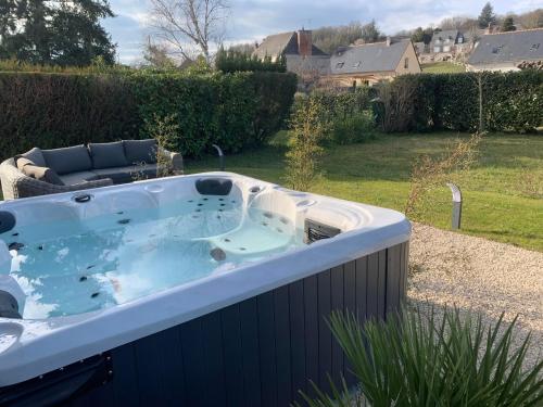 bañera de hidromasaje en un patio con sofá en Havre de paix spa proche Amboise & châteaux de la Loire, en Noizay