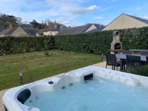 bañera de hidromasaje en un patio con mesa en Havre de paix spa proche Amboise & châteaux de la Loire, en Noizay