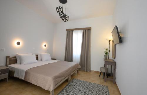 a white bedroom with a bed and a television at Verano Apartments in Kalymnos