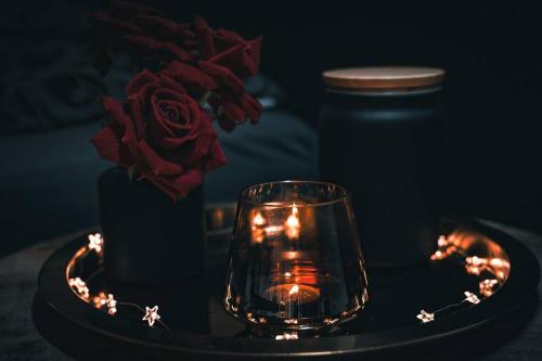 a glass on a table with a candle and a rose at Luxus Loft Whirlpool Designer Küche Bad in Herdecke
