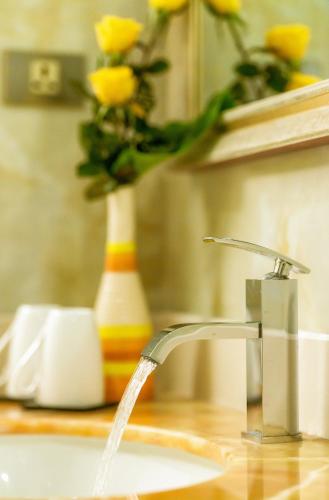 a sink with a faucet and a vase with yellow roses at Muong Thanh Grand Bac Giang Hotel in Bắc Giang