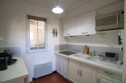 a kitchen with white cabinets and a sink and a window at SUITE CHARABOIS in Saint-Raphaël