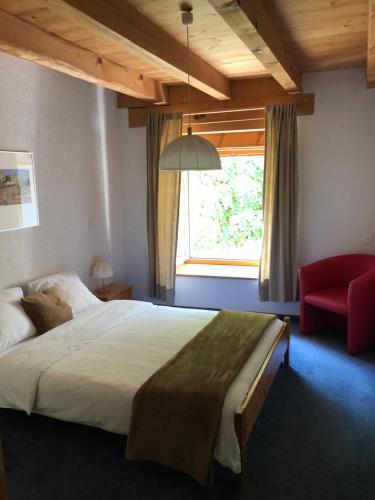 a bedroom with a large bed and a red chair at Auberge de la Bouege in Le Noirmont
