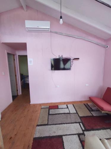a living room with a tv on a white wall at Cabañas Isabella in Chonchi