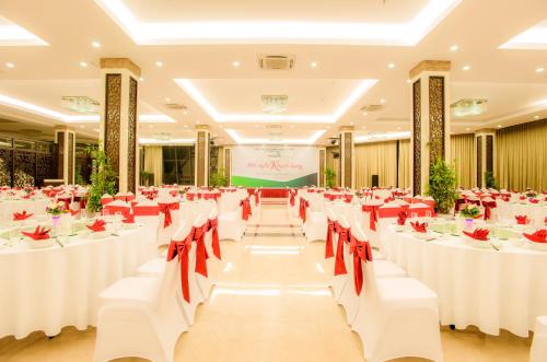 a banquet hall with white tables and red chairs at Muong Thanh Grand Bac Giang Hotel in Bắc Giang