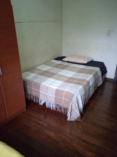 a small bedroom with a bed with a plaid blanket at Residencias MARGARITA in Manizales
