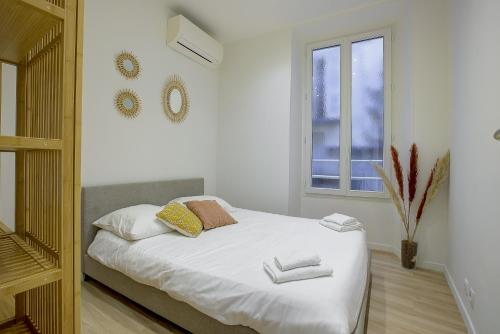 une chambre avec un lit avec des draps blancs et une fenêtre dans l'établissement Maison Bianchi - Raspail, à Nice