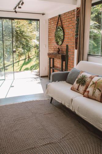 a living room with a couch and a large window at Pousada Refúgio do Vale - Praia do Rosa in Praia do Rosa