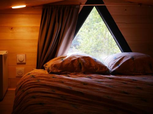 a bed with two pillows in front of a window at Tiny house ocean in Naujac-sur-Mer