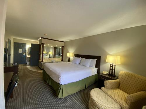 a hotel room with a bed and two chairs at Days Inn by Wyndham Perryville in Perryville
