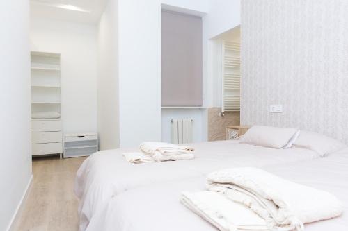 Dos camas en una habitación blanca con toallas. en Apartamento DENVER - Centro, Nuevo, Diseño, Wifi en Valladolid
