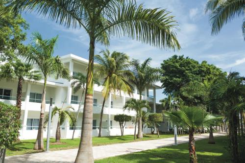 un edificio con palmeras delante en Riu Playacar - All Inclusive en Playa del Carmen