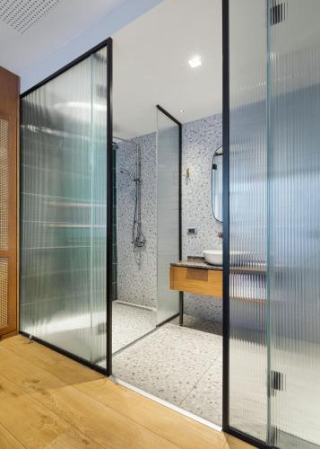 a glass pivot door in a bathroom with a sink at Galata Rasso Hotel in Istanbul