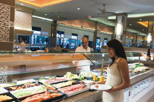 a woman holding a plate of food in a buffet at Riu Playacar - All Inclusive in Playa del Carmen