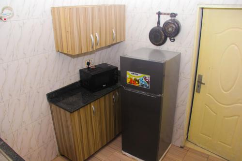 a small kitchen with a refrigerator and a microwave at Unique 1BEDROOM Shortlet Stadium Rd with 24hrs light-FREE WIFI -N58,000 in Port Harcourt