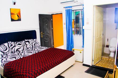 sypialnia z łóżkiem w kolorze czerwonym i białym oraz drzwiami w obiekcie Unique 1BEDROOM Shortlet Stadium Rd with 24hrs light-FREE WIFI -N35,000 w mieście Port Harcourt