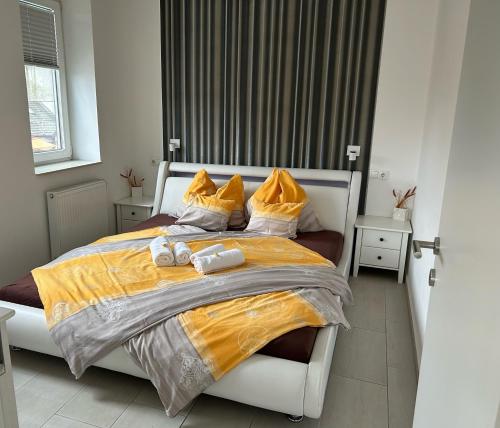 a bedroom with a large bed with yellow blankets and pillows at Azúr Ház Viola Apartman in Sárvár