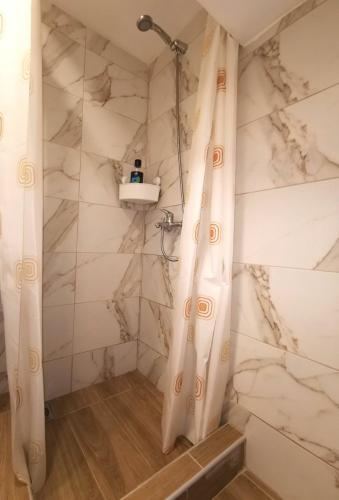 y baño con ducha y paredes de mármol blanco. en Dunja Apartmans, en Belgrado