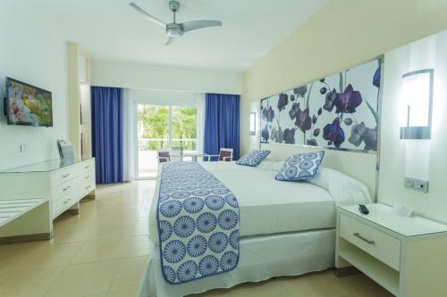 a bedroom with a large bed with blue and white sheets at Riu Playacar - All Inclusive in Playa del Carmen