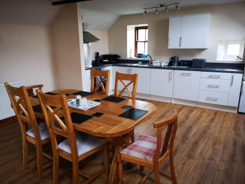 a kitchen with a wooden table and chairs in a room at The Barn in Durham