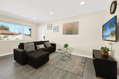 a living room with a black couch and a glass table at Sunny & Cheerful Near I-10 Queen Beds w Parking! in Alhambra