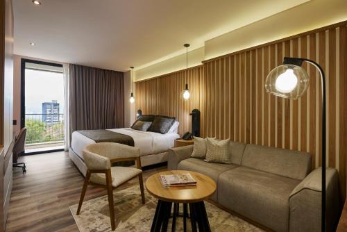a hotel room with a bed and a couch at Blues Suites Medellín in Medellín