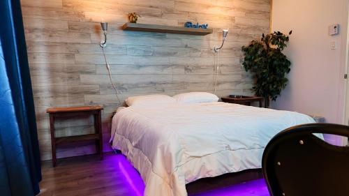 a bedroom with a white bed with a wooden wall at Petit studio très intime, avec spa intérieur au coeur de Shawinigan in Shawinigan