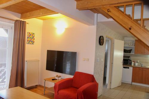 a living room with a red chair and a flat screen tv at Chata Větrník u Černého dolu v Krkonoších in Lauterwasser