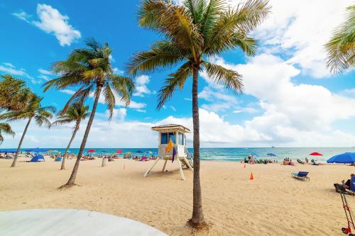 una playa con palmeras y una torre de salvavidas en Coco Bay Vacation Condos en Fort Lauderdale