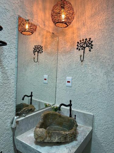 a bathroom with a mirror and a sink with a rock at Pousada Preciosa do Arraial - com Natura e L'Occitane - recém inaugurada in Arraial d'Ajuda