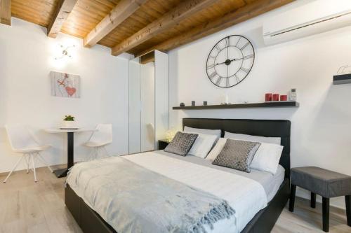 Antico Loft Como في كومو: غرفة نوم بسرير كبير وساعة على الحائط