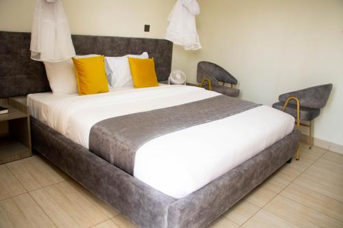 1 dormitorio con 1 cama blanca grande con almohadas amarillas en Distinction Gardens, en Siaya