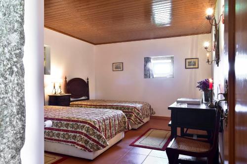 ein Hotelzimmer mit zwei Betten und einem Schreibtisch in der Unterkunft Casa da Quinta do Cruzeiro in Fontoura