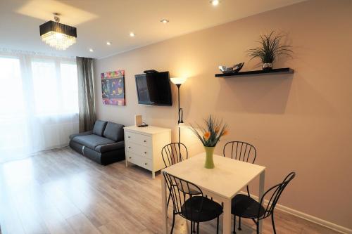 a living room with a table and chairs and a couch at KGHN Apartments Wyszyńskiego in Szczecin