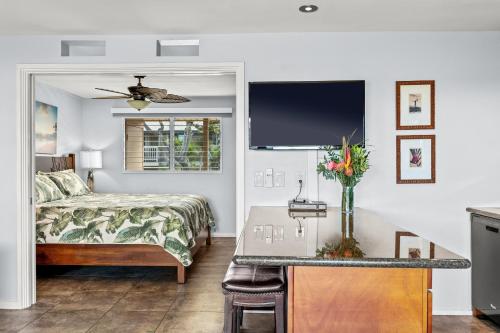a bedroom with a bed and a table with flowers on it at Wailana Sands 206 in Kihei