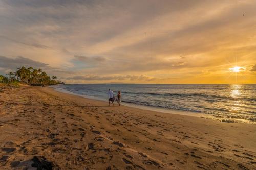 two people walking on the beach at sunset at Wailana Sands 206 in Kihei