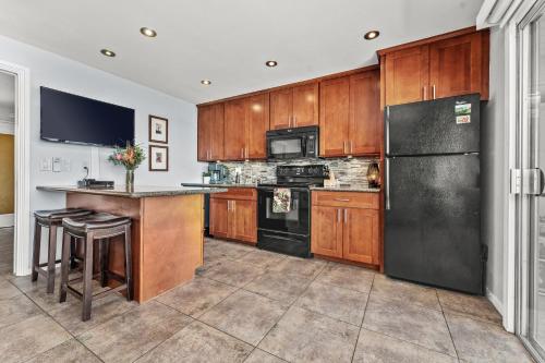 a kitchen with wooden cabinets and a black refrigerator at Wailana Sands 206 in Kihei