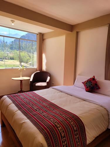 a bedroom with a bed with a window and a chair at Ayllu B&B Ollantaytambo in Ollantaytambo