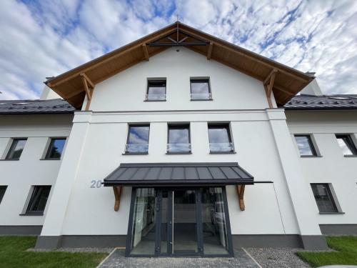 a white building with a gambrel roof at Apartament Pod Ojcowem in Skała