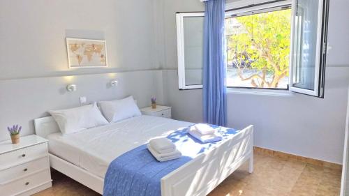 a bedroom with a white bed and a window at My Cretan Village by Go4sea in Chorafakia