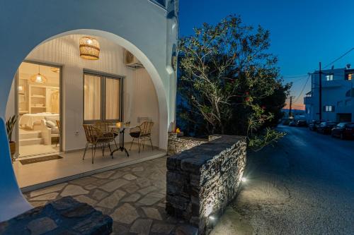 une maison avec une arche, une table et des chaises dans l'établissement Adama's Suites, à Naxos Chora