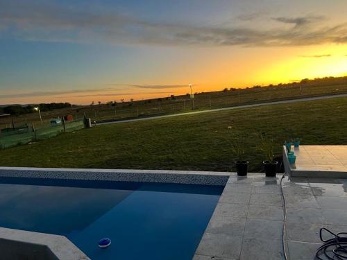 una piscina con puesta de sol en el fondo en Villa General Belgrano Lago Los Molinos in 