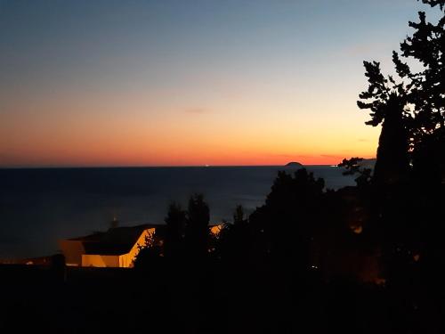 a sunset over the ocean with trees in the foreground at Bressa de Ma affittacamere, room & breakfast in Pietra Ligure