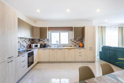 a kitchen with wooden cabinets and a blue couch at H2 -Modern and Spacious 3 Bedroom Apartment in San Ġwann