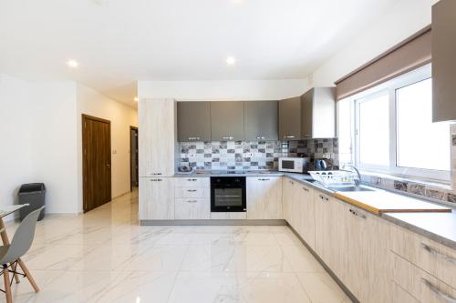 a kitchen with stainless steel appliances and a large window at H2 -Modern and Spacious 3 Bedroom Apartment in San Ġwann