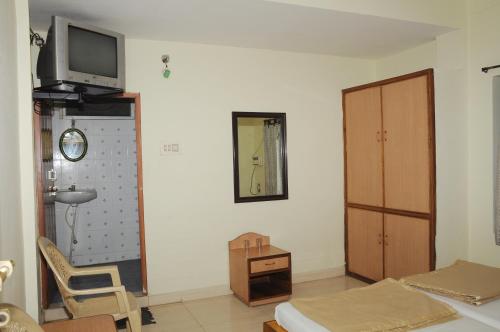 a living room with a tv on the wall and a chair at Hotel Agarala Residency in Tirupati
